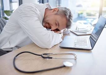 Image showing Man, doctor and laptop sleeping on desk from burnout, overworked or insomnia at the office. Tired male medical professional taking a nap, rest or asleep on table by computer at the workplace