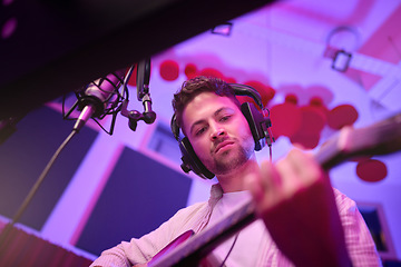 Image showing Man, musician or guitar in neon studio, recording production or live performance for radio, label or low angle audio. Guitarist, artist or person playing strings instrument on headphones in practice