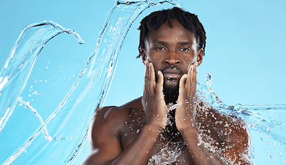 Image showing Water splash, facial skincare and portrait of black man with hands on face, morning cleaning isolated on blue background. Hygiene, male model and grooming for health, wellness and skin care in studio