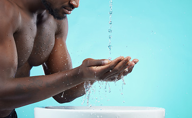 Image showing Water drops, black man and cleaning hands with skin, washing face and skincare isolated on blue background. Mockup space, clean body and natural cosmetics with grooming, hygiene and beauty in studio