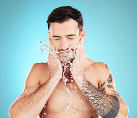 Image showing Water splash, skincare and man with hands on beard, morning cleaning treatment isolated on blue background. Facial hygiene, male model and grooming face for health, wellness and skin care in studio.