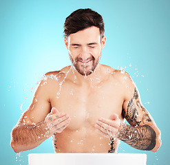 Image showing Water splash, facial skincare and man with cleaning face, morning detox treatment isolated on blue background. Hygiene, male model and grooming for health, wellness and skin care or beauty in studio.