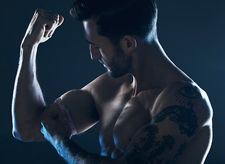 Image showing Muscle, showing and man with arms in the dark for fitness isolated on a studio background. Exercise, training and muscular bodybuilder flexing a bicep for workout results, performance and progress