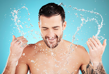 Image showing Water, skincare and man with facial splash, smile and morning cleaning treatment isolated on blue background. Face, hygiene and male model grooming for health, wellness and clean skin care in studio.