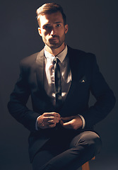 Image showing Businessman, suit and portrait in dark studio for corporate fashion, design or professional aesthetic. Young executive leader, model and focus for vision, entrepreneur mindset or tattoo by background