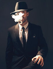 Image showing Mafia, portrait and man with smoke in a suit for fashion isolated on a dark background in a studio. Sexy, vintage and businessman looking stylish, gangster and rich while smoking on a studio backdrop