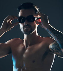 Image showing Fitness, sports and face of swimmer with goggles isolated in studio for wellness, exercise and training. Workout, swimming athlete and man focus on dark background with muscle, strong body and tattoo