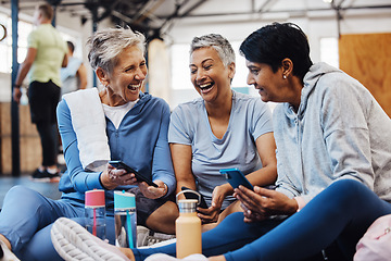 Image showing Gym, smartphone and senior women laughing at meme on phone after fitness class, conversation and comedy on floor. Exercise, bonding and happy mature friends checking social media together at workout.
