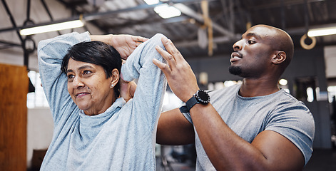 Image showing Coach, personal trainer and senior woman stretching arms in gym with black man for flexibility. Physiotherapy, training and elderly female with trainer helping with workout and exercise for health.