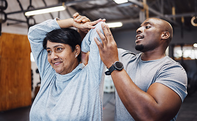 Image showing Personal trainer, coach and senior woman stretching arms in gym with black man for flexibility. Sports, training and elderly female with male trainer helping with workout and exercise for health.