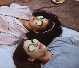 Image showing Facial, cucumber and sleepover with girl best friends lying on the floor together for beauty treatment. Face mask, skincare or natural care with a female and friend at home to relax while bonding