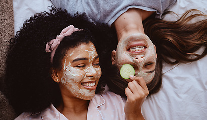 Image showing Facial, cucumber or beauty with girl best friends lying on the floor together for treatment at a sleepover. Face mask, skincare or natural care with a female and friend at home to relax while bonding