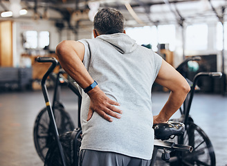 Image showing Sports, gym and injury, old man with back pain, emergency during workout at fitness studio. Health, wellness and inflammation, senior person with hand on muscle cramps while training on exercise bike