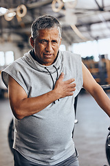 Image showing Fitness, gym and old man with pain in chest, medical emergency during workout at sports studio. Exercise, health and wellness, stress and tired senior person with hand on heart muscle while training.