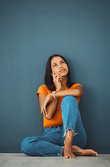 Image showing Woman on ground, thinking and decision for opportunity, ideas and girl daydreaming on blue studio background. Female with imagination, lady on floor and wondering with focus, mindset and thoughts