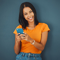 Image showing Internet, portrait and phone by woman on social media, mobile or app browsing a website, web or texting. Happy, smiling and female typing online isolated against a studio blue background