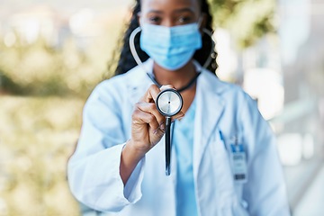 Image showing Covid, doctor and stethoscope at hospital with mask for compliance, safety and healthcare on bokeh background. Checkup, corona and female health expert at clinic for help, goal and innovation outside