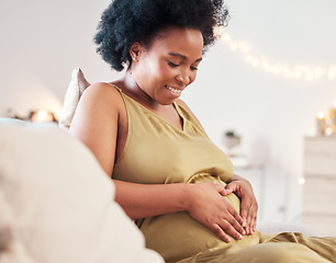 Image showing Pregnant stomach, heart hand sign and happy black woman feeling mother hope and love. Mom care, sofa and living room lounge with a person holding abdomen happy about pregnancy and baby in a house