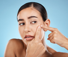 Image showing Woman, face and pop pimple with hands and acne, anxiety and stress, beauty and skincare isolated on blue background. Skin problem, facial and cosmetics, dermatology and cosmetic care in studio