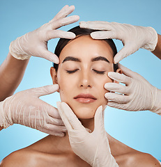 Image showing Plastic surgery, beauty and hands on the face of a woman isolated on a blue background in a studio. Feeling, skincare and doctors touching a model for a botox, cosmetics or dermatology consultation