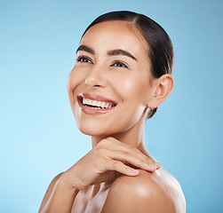Image showing Woman, face and smile, happy and beauty with natural cosmetics and glow isolated against blue background. Clean, cosmetic care and hand with facial, makeup and healthy skin with skincare in studio