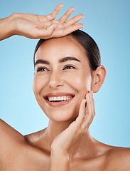 Image showing Woman, face and smile, happiness and beauty with natural cosmetics and glow isolated on blue background. Clean, cosmetic care and hands with facial, makeup and healthy skin with skincare in studio