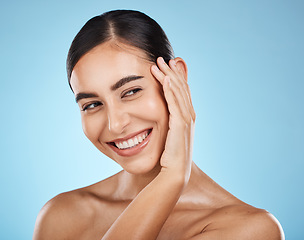 Image showing Woman, face and smile, happy and skin with natural cosmetics and beauty isolated against blue background. Clean, cosmetic care and hand with facial, makeup and healthy glow with skincare in studio