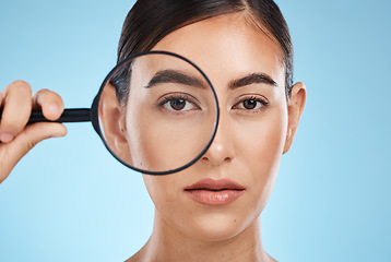 Image showing Woman, face with magnifying glass, eyes and beauty in portrait, eye care and vision isolated on blue background. Skincare cosmetics, skin and facial inspection, mockup space and dermatology in studio