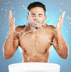 Image showing Water splash, facial and man in studio for skincare, wellness and grooming on blue background. Cleaning, beauty and moisture by Mexican model relax with luxury, routine and face treatment isolated