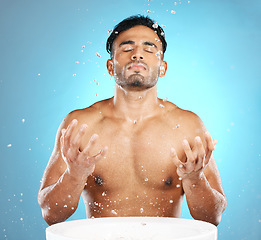 Image showing Facial, skincare and man in studio for water splash, wellness and grooming on blue background. Cleaning, beauty and moisture by Mexican model relax with luxury, routine and facial wash while isolated