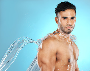 Image showing Water splash, portrait and man for beauty, skin and skincare cleaning his body, muscle and topless. Mexican, strong and serious model with moisture, cleanse and hydration in studio blue background