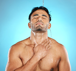 Image showing Water, shower and man cleaning skin, beauty and skincare for his body, muscle and topless. Latino, male and wellness model with moisture, cleanse and hydration isolated in studio blue background