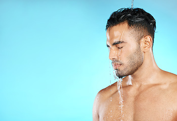 Image showing Water splash, shower and man in studio for skincare, wellness and grooming on blue background. Cleaning, beauty and moisture by Mexican model relax with luxury, routine and body care while isolated