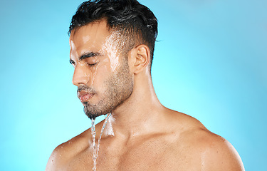 Image showing Shower, skincare and man in studio for water splash, hygiene and grooming on blue background. Cleaning, skin and Mexican model relax with luxury, moisture and wash routine while standing isolated