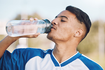 Image showing Drinking water, bottle and soccer or football player on a sports field on a break after match or competition. Man, athlete and sportsman refreshing during a game happy and smiling for due to fitness