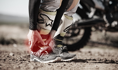 Image showing Ankle, injury and motorcycle with the hands of a man holding his joint in pain while outdoor for a race. Sports, training or anatomy with a male athlete suffering an accident on a ride for recreation