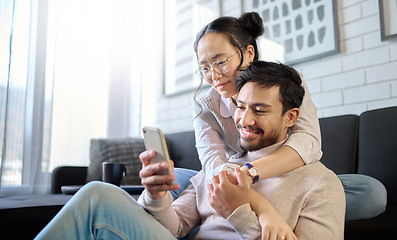 Image showing Phone, love and diversity with a couple in their home, bonding while browsing social media in the living room. Mobile, communication or internet with an interracial man and woman together in a house