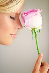 Image showing Flower, romance and woman in a studio with a rose for a fragrance, scent or aroma to smell. Floral, cosmetic and female model from Australia with a natural beauty makeup routine by a gray background.