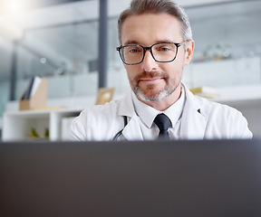 Image showing Laptop, man and doctor working in hospital for healthcare, health and wellness in clinic. Computer research, medical professional or mature physician writing report, telehealth or online consultation