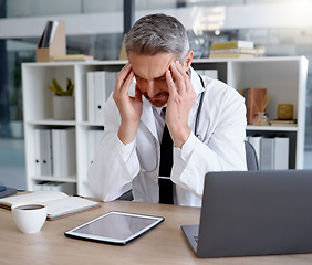 Image showing Doctor, burnout and man with headache in hospital feeling depressed while working on laptop. Mental health, depression and medical professional or physician with stress, pain and anxiety in clinic.