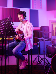 Image showing Musician, headphones or guitar in neon studio, recording production or performance on radio mic, label or band concert. Guitarist, artist or man playing on strings instrument in night light practice