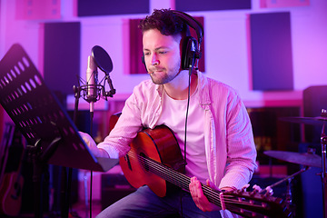 Image showing Man, headphones or guitar in neon studio, recording production or performance on radio mic, label or band concert. Guitarist, artist or thinking musician on strings instrument in night light practice