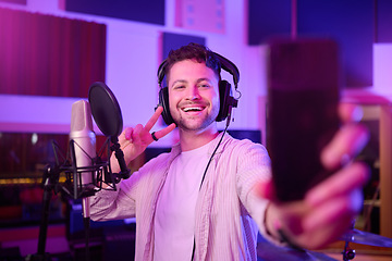 Image showing Singer in recording studio, selfie and portrait with peace hand sign, music with mic and headphones. Social media content, happy in picture and audio, podcast or radio dj with man smile with phone