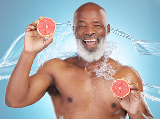 Image showing Black man, portrait smile and grapefruit for skincare nutrition, vitamin C or hydration against a blue studio background. Happy African American male smiling and holding fruit for health and wellness