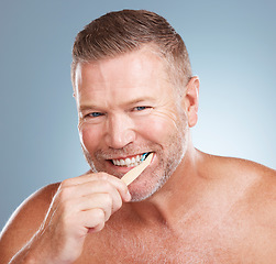 Image showing Happy, mouth or old man brushing teeth with dental toothpaste products for healthy oral hygiene in studio. Eco friendly, portrait or senior person cleaning gums with a natural bamboo wood toothbrush