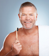 Image showing Happy, portrait or old man brushing teeth with dental toothpaste for healthy oral hygiene grooming in studio. Eco friendly, smile or senior person cleaning gums with a natural bamboo toothbrush