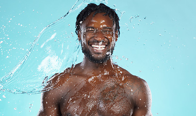 Image showing Water splash, beauty and black man isolated on blue background for face cleaning, body shower and skincare. Strong, muscle and happy model or person facial glow in studio headshot washing or hygiene