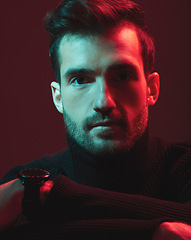 Image showing Portrait, serious and red with a handsome man model in studio on a dark background for contemporary fashion. Face, beauty and art with a young male posing indoor to promote trendy clothes or style