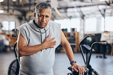 Image showing Gym, pain in chest and senior man with medical emergency during sports workout at fitness studio. Health, wellness and inflammation, old man with hand on heart attack while training on exercise bike.