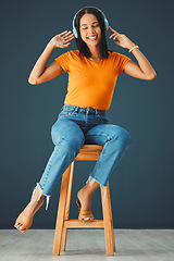 Image showing Woman, headphones and listening to music while dancing and streaming online on a studio background. Happy gen z person with headset for podcast, radio or audio sound on chair to relax for freedom